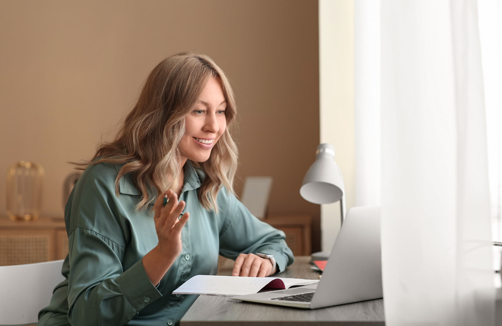 Writing tutor smiling during an online session at her desk
